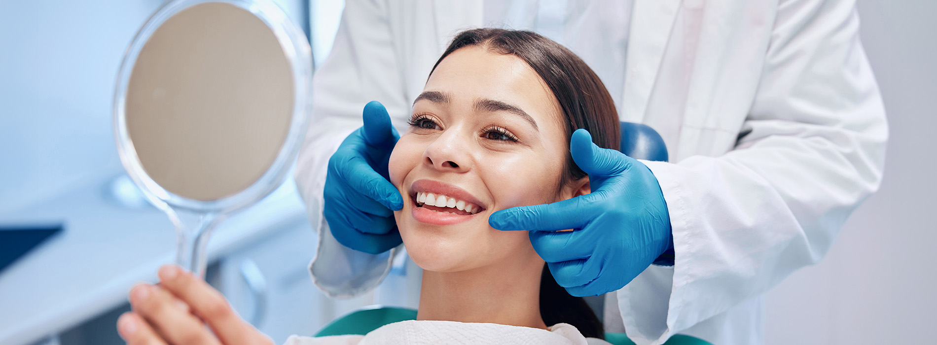 A dental hygienist performing a teeth cleaning procedure on a patient while wearing personal protective equipment.