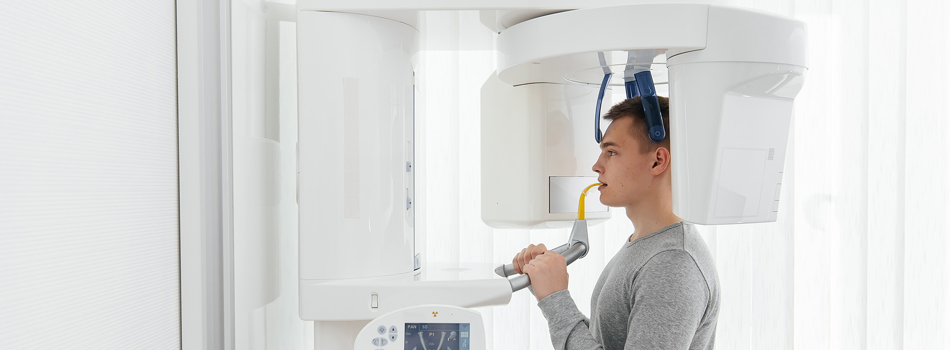 A person standing next to a large, white MRI machine with their head inside the scanner.