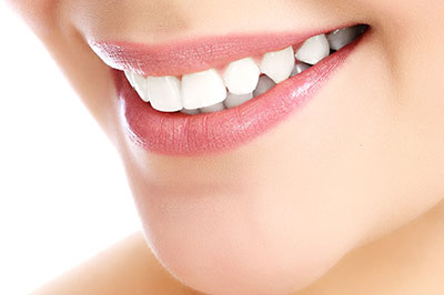 The image features a close-up of a person s face with a focus on their teeth, showcasing a bright smile and lipstick, against a white background.