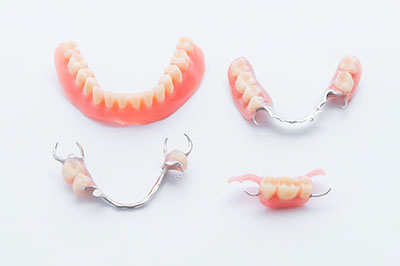 The image displays a set of dentures with false teeth arranged on a white background, showcasing different styles and sizes.