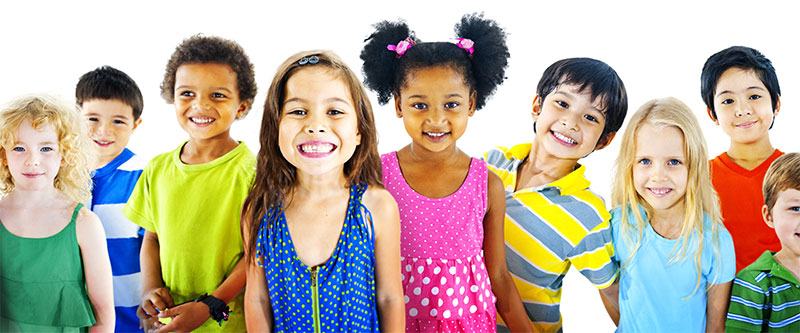 The image shows a group of children posing together with bright smiles, wearing colorful clothing against a plain background.