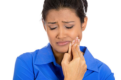 Woman with her eyes closed, holding her nose, possibly in discomfort.