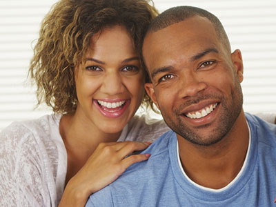 The image depicts a man and woman posing together with smiles on their faces.