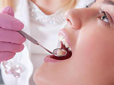 An image featuring a woman receiving dental treatment from a professional, with the focus on the dental procedure being performed.