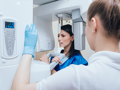 The image shows two individuals, likely medical professionals, working with advanced imaging equipment, possibly in a radiology or diagnostic setting.