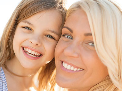 A young girl and an adult woman smiling at the camera.